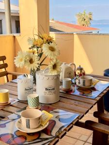 阿尔盖罗Appartamento Francesca的阳台上的桌子上放着杯子、盘子和鲜花