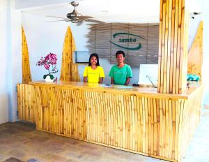 吉利特拉旺安桑巴海滨景观别墅酒店的两人站在带冲浪板的木柜台后面