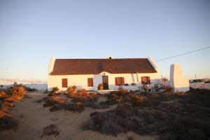 HondeklipbaaiFisherman's Cottage的一间白色的小房子,有棕色的屋顶