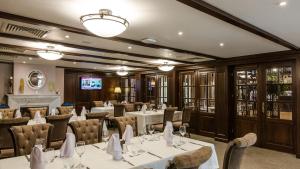 布加勒斯特河拉斯特劳酒店的餐厅配有白色的桌椅和电视