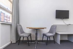 格莱内尔格Hi 5 Glenelg Studio Apartment的配有电视的客房内的一张桌子和两把椅子