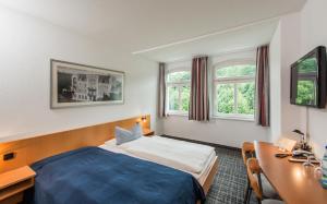艾森纳赫城市酒店的酒店客房设有一张床、一张书桌和窗户。