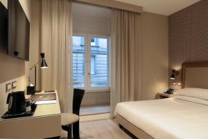 那不勒斯卡鲁索广场精品和健康套房酒店的配有一张床、一张书桌和一扇窗户的酒店客房