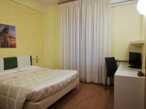 兰恰诺罗马酒店的一间卧室配有一张床、一张书桌和一台电视