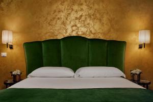 威尼斯桑丽欧旅游酒店的一张带绿色床头板和两个枕头的床