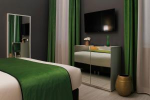 威尼斯桑丽欧旅游酒店的一间卧室配有一张带绿色窗帘的床和电视。