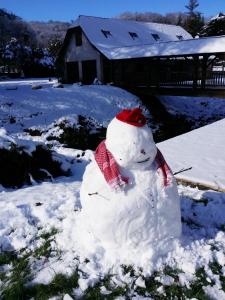 GanMaison du bonheur的雪人坐在雪地里,戴着红帽