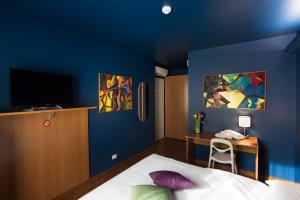 乌迪内Albergo Residenza Al Teatro的一间卧室设有蓝色的墙壁、一张床和一张书桌