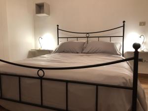 卡斯泰拉内塔Il Pendio的一张带黑色框架和白色床单及枕头的床