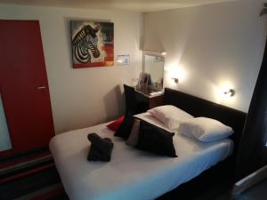 桑特Kyriad Direct Saintes的一间卧室配有带白色床单和黑色枕头的床。