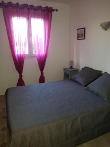 圣马迪拉莫Appartement de l'olivier的一间卧室配有一张带紫色窗帘的床和窗户。