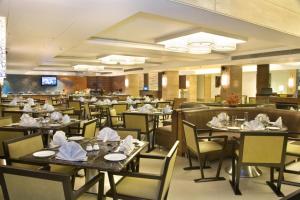 加尔各答索奈特酒店的餐厅配有桌椅和餐巾