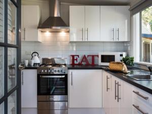 戴尔斯福特Gumnut Cottage Daylesford的厨房配有白色橱柜和炉灶烤箱。
