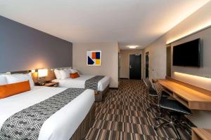 卡莱尔Microtel Inn & Suites by Wyndham Carlisle的酒店客房设有两张床和一台平面电视。