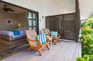 拉迪格岛拉迪格诺迪克海滨酒店的门廊上的卧室配有2把椅子和1张床