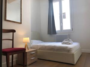 佛罗伦萨San Frediano Apartment的一间卧室设有两张床、一把椅子和一个窗户。
