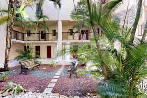迈尔斯堡海滩Ocean Breeze & Santa Maria Condos的一座带长凳和棕榈树的建筑的庭院