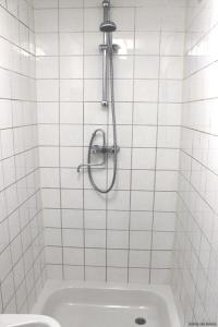 鹿特丹新海洋乐园酒店的白色瓷砖浴室设有淋浴和水槽