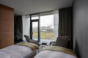 格林达维克The Retreat at Blue Lagoon Iceland的酒店客房设有两张床和大窗户。