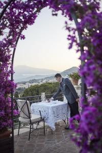 陶尔米纳Grand Hotel Timeo, A Belmond Hotel, Taormina的穿着西服的男人,站在桌子上,穿着桌布