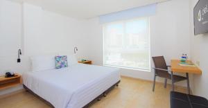 圣玛尔塔Del Mar Hotel的一间卧室配有一张床、一张书桌和一个窗户。