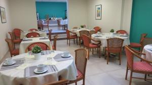 比亚里茨梅尔欧仁妮高尔夫酒店的用餐室配有桌椅和白色的桌布