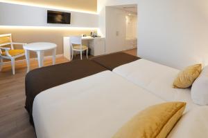 卡塔赫纳塞尔科蒂尔阿方索十三世酒店的卧室配有白色的床和桌椅