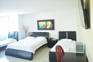 巴兰基亚国际套房宾馆的一间卧室配有两张床、一张桌子和一台电视。