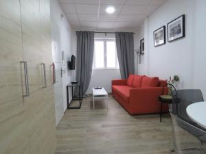 塞维利亚Living Sevilla Apartments Hércules的客厅设有红色的沙发和窗户。