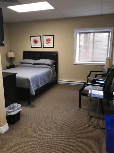 克拉伦维尔Riverview Suites的一间卧室设有一张床、一个窗口和一把椅子