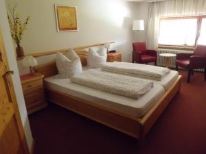 施卢赫湖维森格伦德膳食公寓酒店的一间卧室设有两张床、一把椅子和一个窗户。