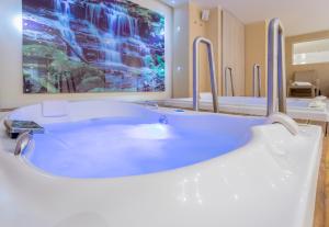 波哥大GHL首都酒店的浴室设有浴缸,墙上挂着一幅大画