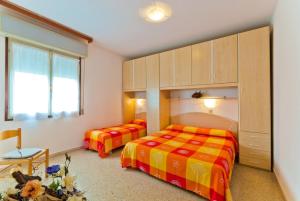 比比翁Apartment in Bibione 24425的一间卧室设有两张床、橱柜和一张桌子。