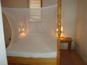 萨利波图尔科尔玛雅公寓式酒店的一张带白色床单和一张桌子的天蓬床