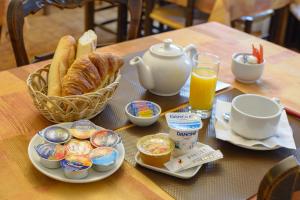 勒布朗-梅尼尔Cit'Hotel Aéro-Hotel的一张桌子,上面有早餐食品和一篮面包及橙汁