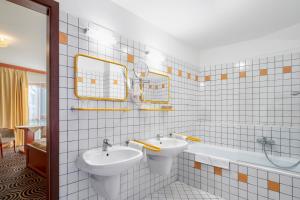 佩奇Sándor Hotel的浴室配有两个盥洗盆和浴缸。