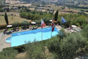 古比奥Agriturismo Castello Di San Vittorino的游泳池配有椅子、遮阳伞和旗帜