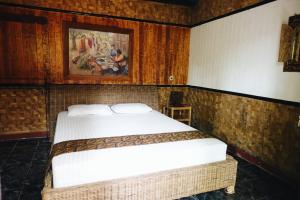 庞岸达兰迷你蒂加民宿的卧室配有一张床,墙上挂有绘画作品