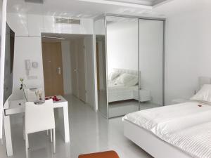 韦伦采Wellness Apartments in Velence的白色卧室配有床和镜子