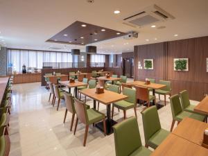 武雄市武雄艾克麦中心酒店的餐厅设有木桌和绿色椅子