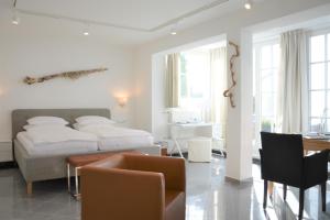 宾茨Atelier-Appartement Ambienta im Zentrum von Binz的白色卧室配有床和桌椅