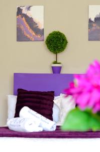 姆巴巴内Rehoboth Mountain Suites的紫色的床,配有白色枕头和盆栽植物