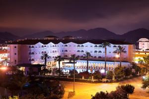 凯麦尔Pashas Princess by Werde Hotels - Adult Only的一座白色的大建筑,晚上种有棕榈树