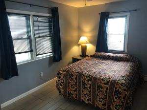 希塞德高地Newly Renovated 2 Bedroom House的一间卧室设有床、两扇窗户和一盏灯。