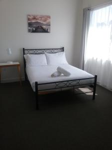 Tullah塔拉小酒馆酒店的一间卧室配有一张带白色床单的床和一扇窗户。