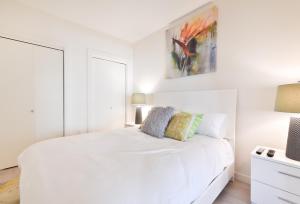 波士顿Global Luxury Suites Downtown Boston的白色卧室配有一张床,墙上挂着一幅画