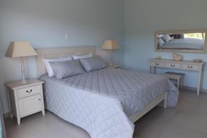 塞吉菲尔德Myoli Holiday Apartments的卧室配有白色床、两个床头柜和镜子