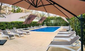 萨洛Salou Med Apartamentos的一组椅子和遮阳伞,位于游泳池旁