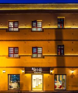 昆明昆明若安·对月楼酒店的一座带窗户和商店的大型黄色建筑