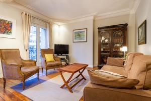 巴黎Greeter-Appartement Haussmannien avec balcon的客厅配有沙发、椅子和电视